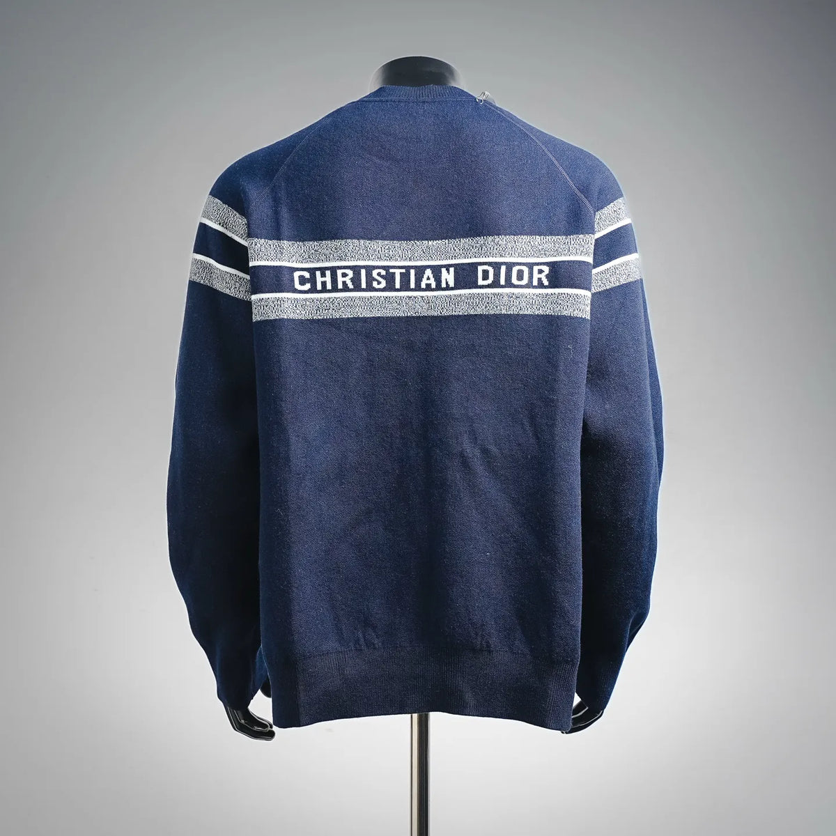Back view Christian Dior solid blue sweater with light gray stripe band and ribbed hem