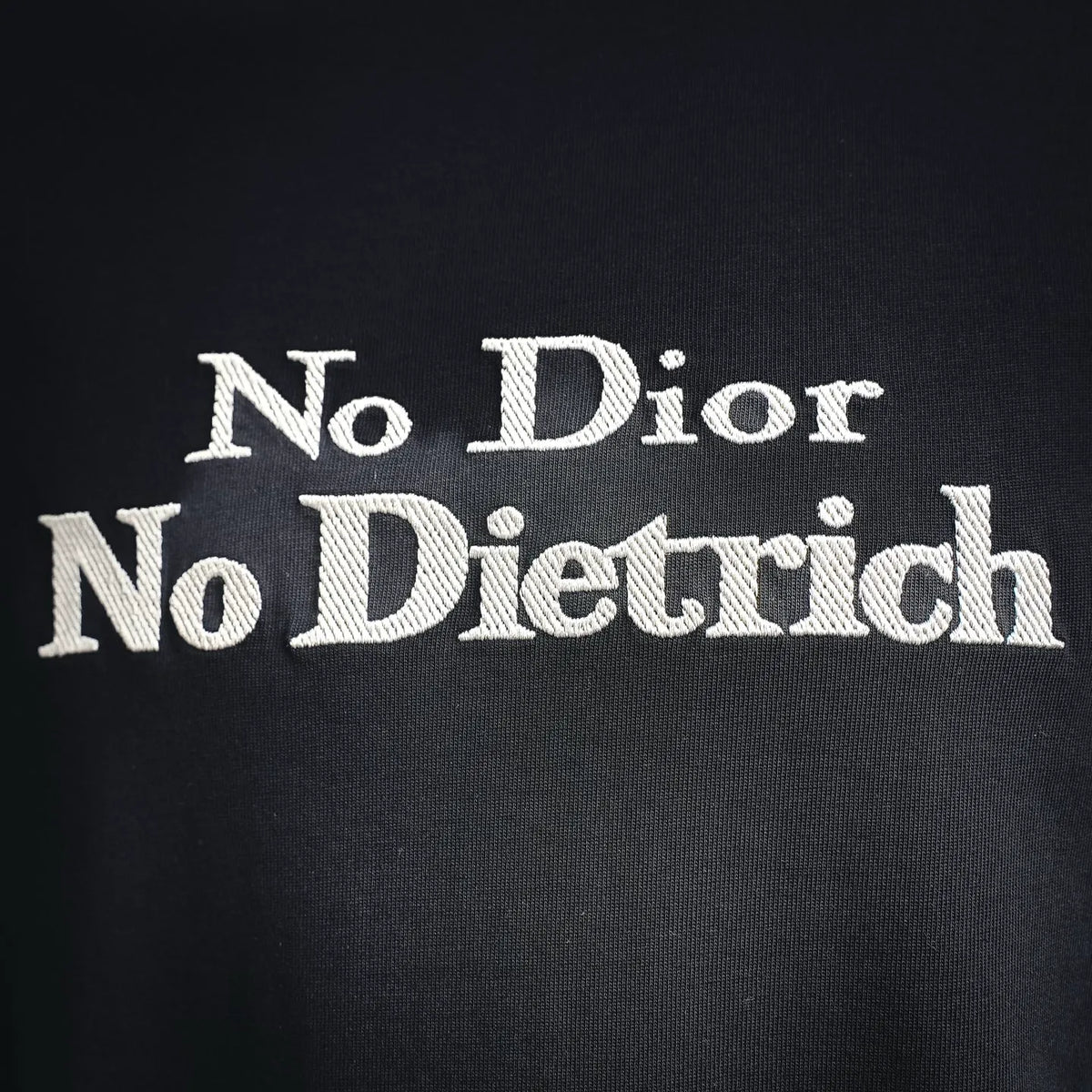 Black crewneck T-shirt close-up of “No Dior No Dietrich” graphic