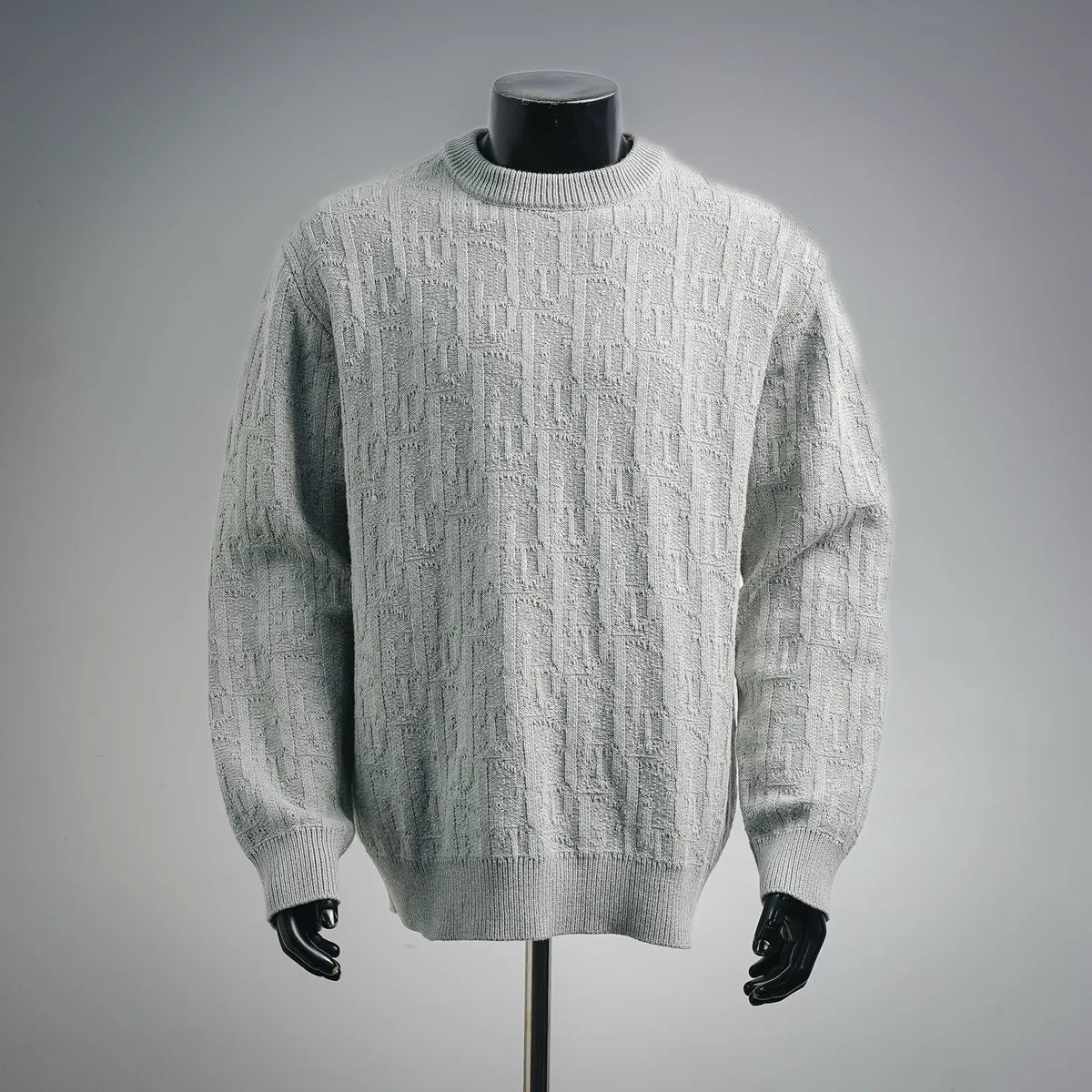 Light gray cable-knit sweater with crew neck and long sleeves