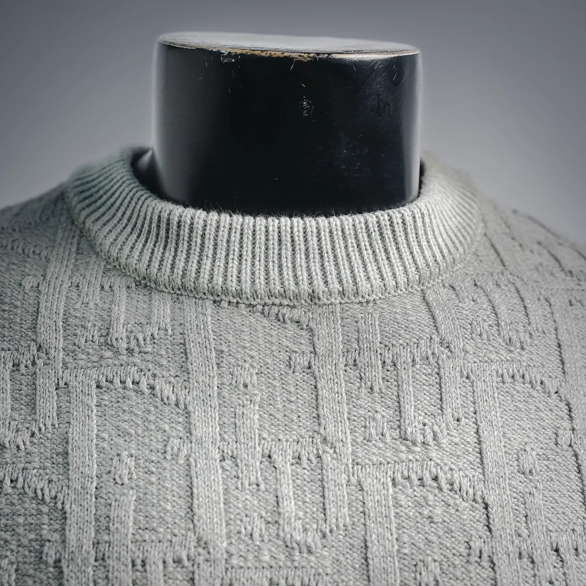Light gray ribbed crew neckline on cable-knit sweater