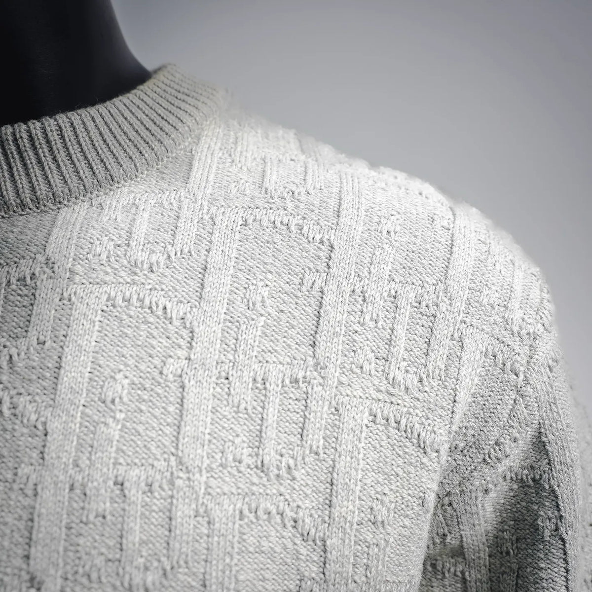Light gray cable-knit sweater with textured stitch detail at shoulder