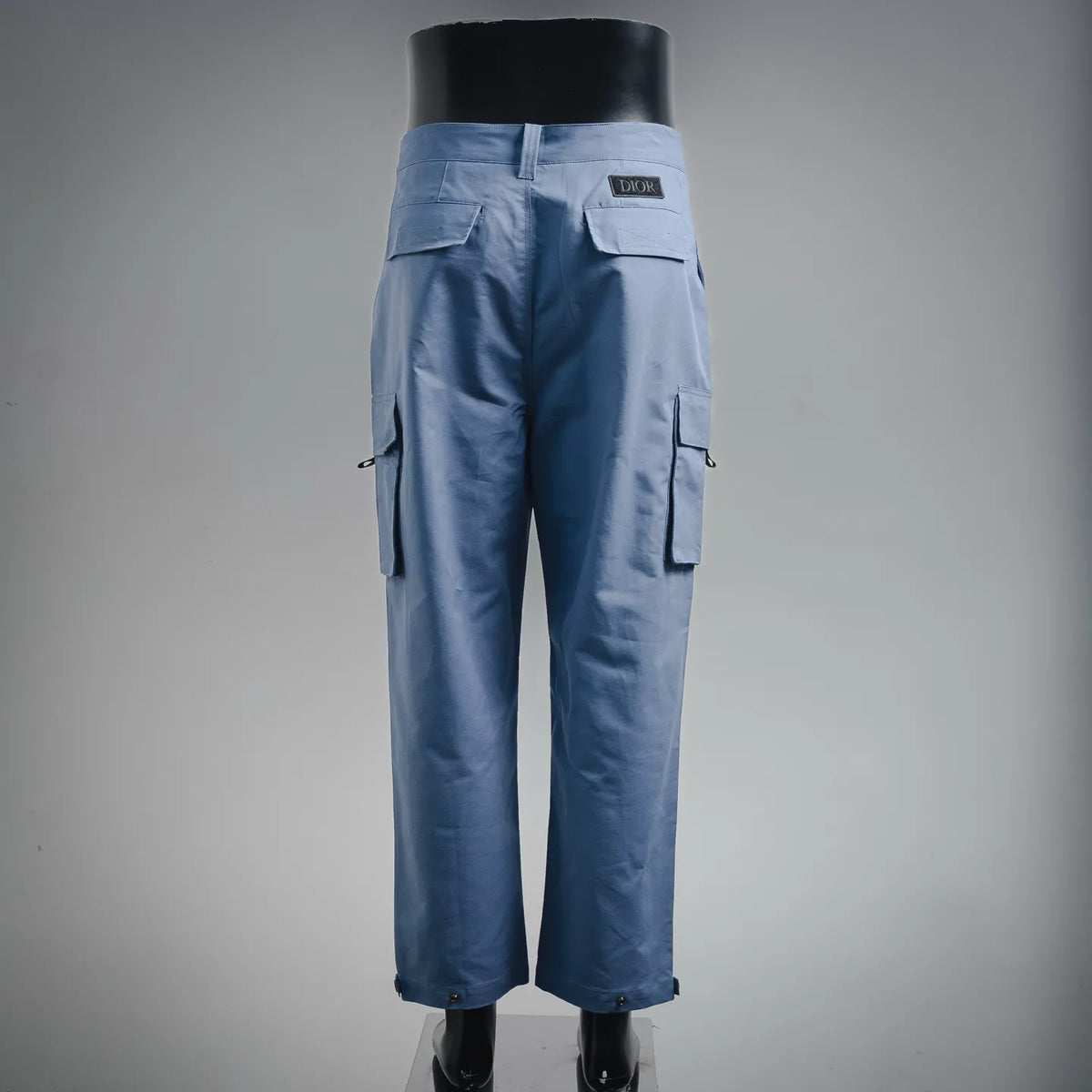 Light blue cargo pants with back yoke, flap pockets, and DIOR patch on waistband.
