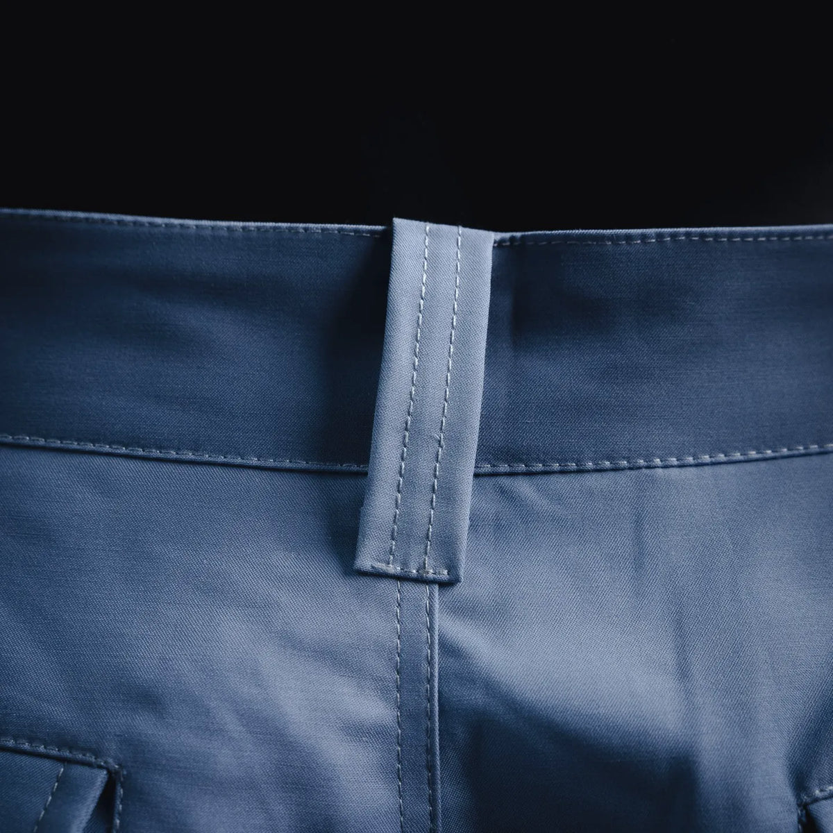 Light blue pants waistband with belt loop and centered stitched closure.