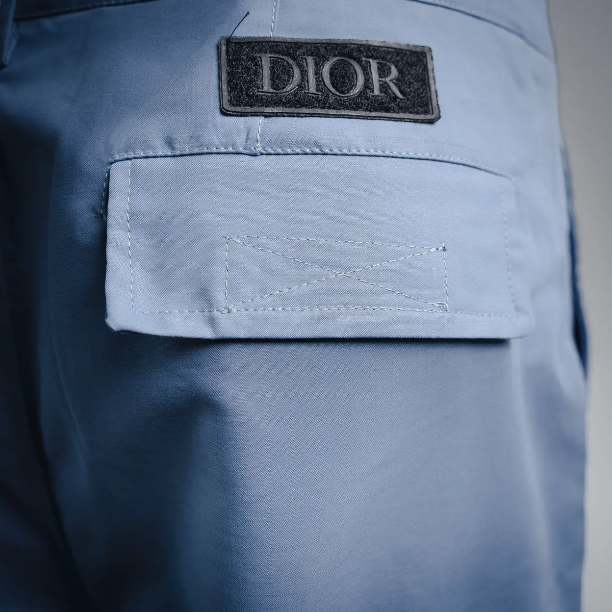 Light blue cargo pants with DIOR label and contrast-stitched flap pocket.