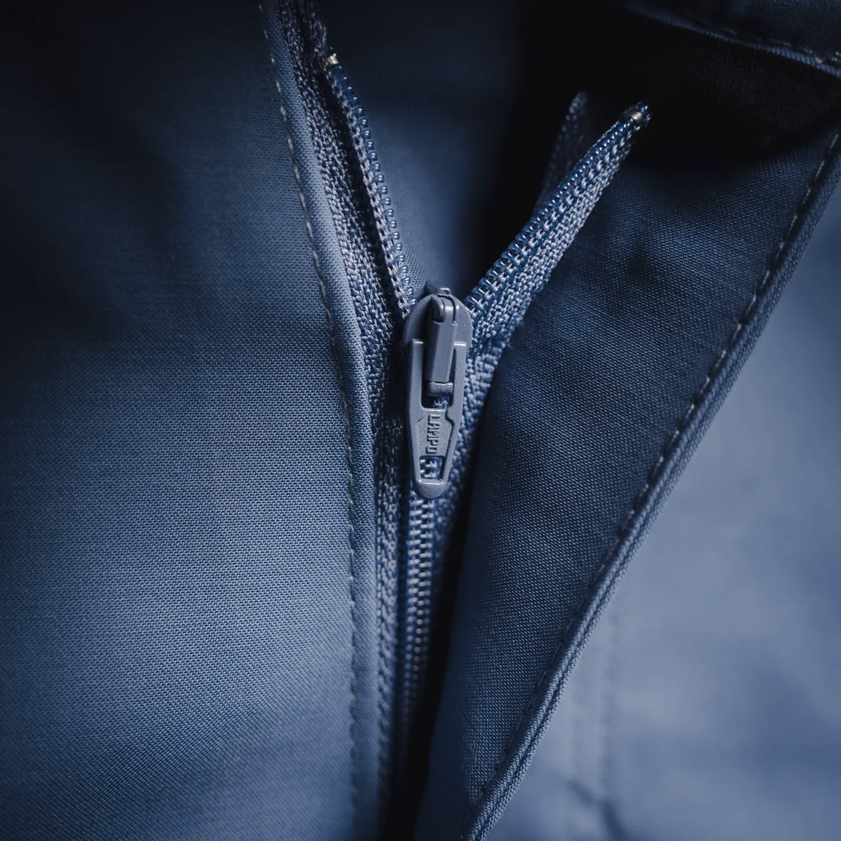 Light blue pants zipper fly with dark zipper pull and stitched seam detail.