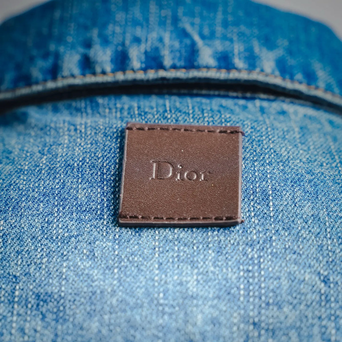 Dior leather-look brand label on light blue denim