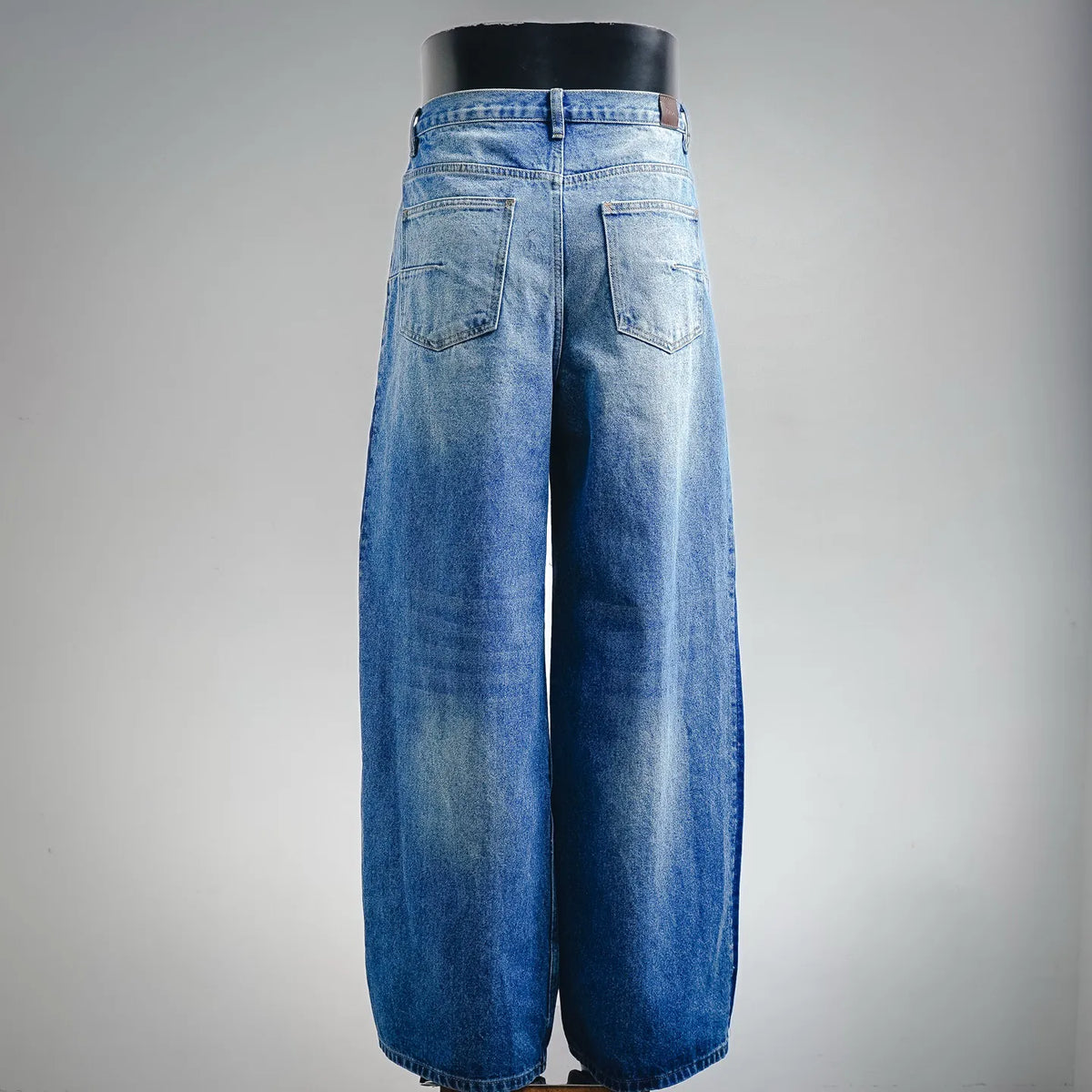 Light blue denim pants with back pockets, yoke seam, and button closure