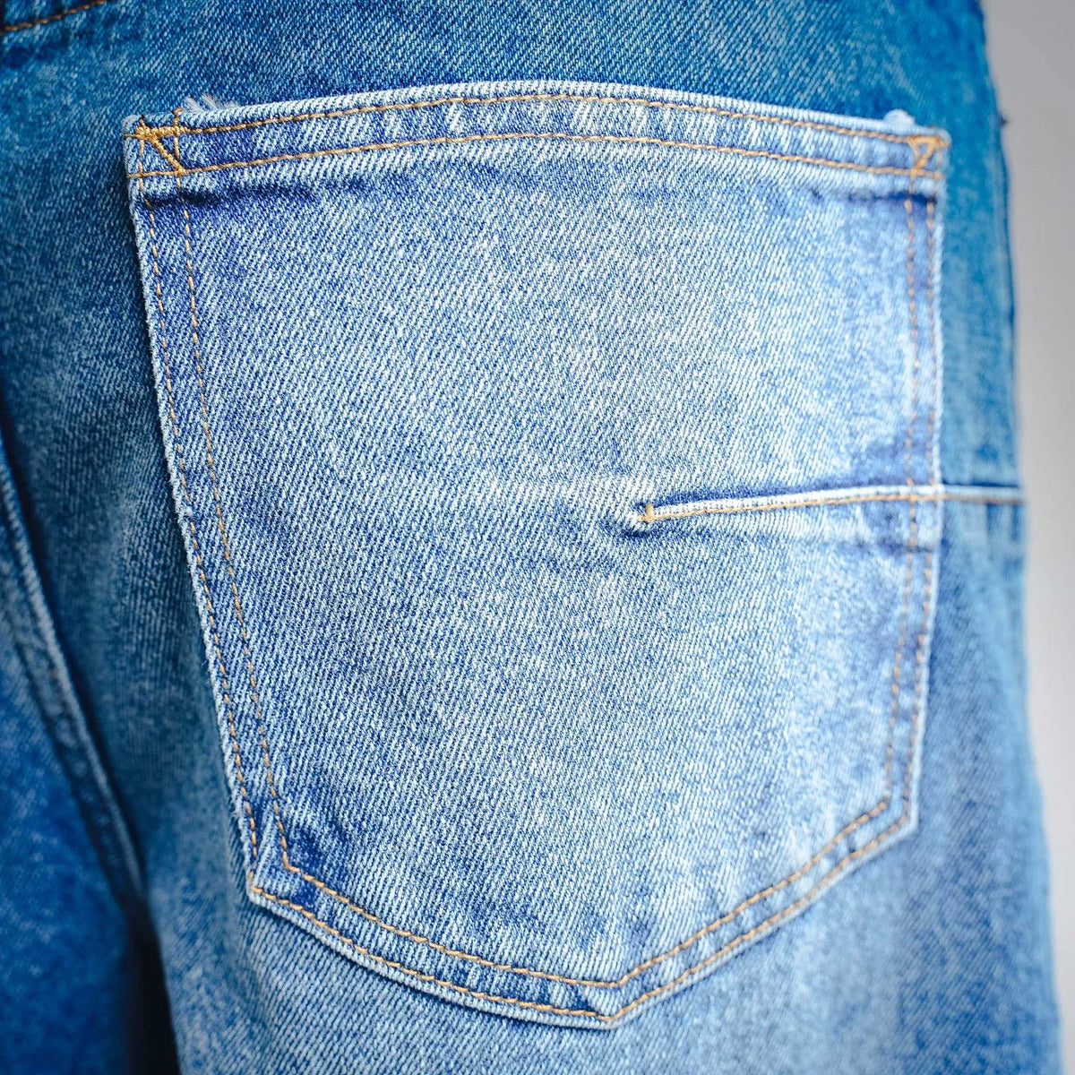 Close-up of light blue denim front pocket with contrast stitching
