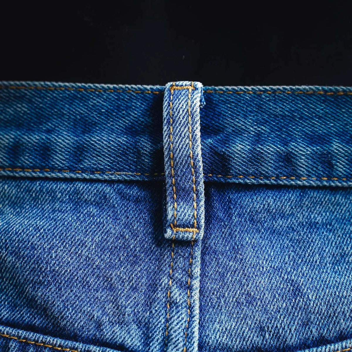 Denim fly front placket with stitched edge and dark button tab