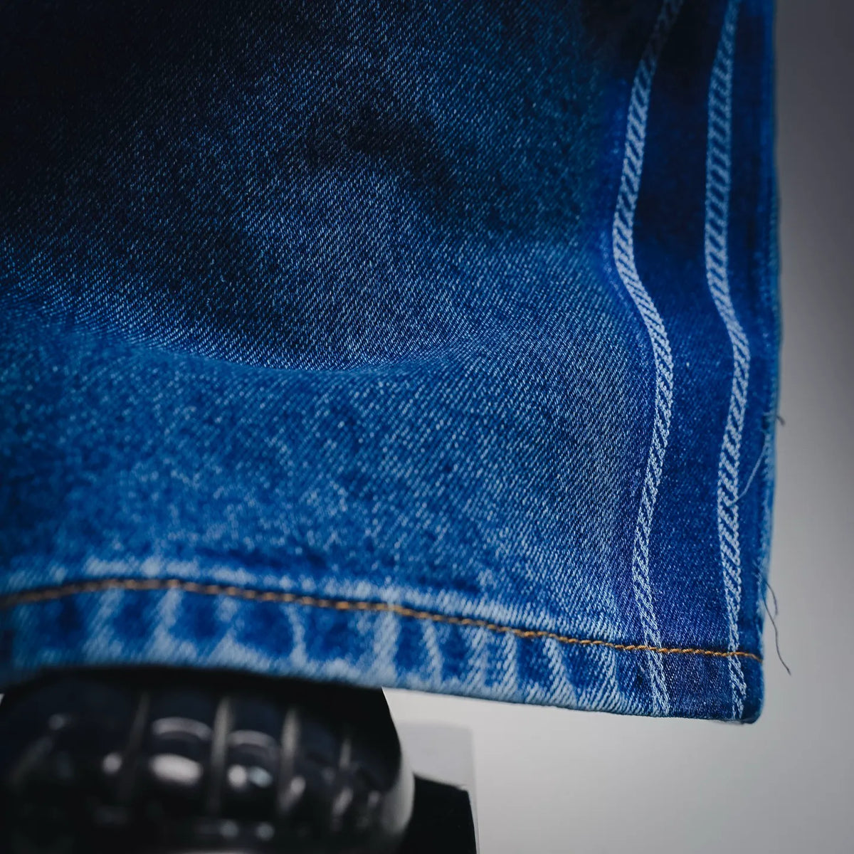Light blue denim hem with contrast topstitching and distressed texture
