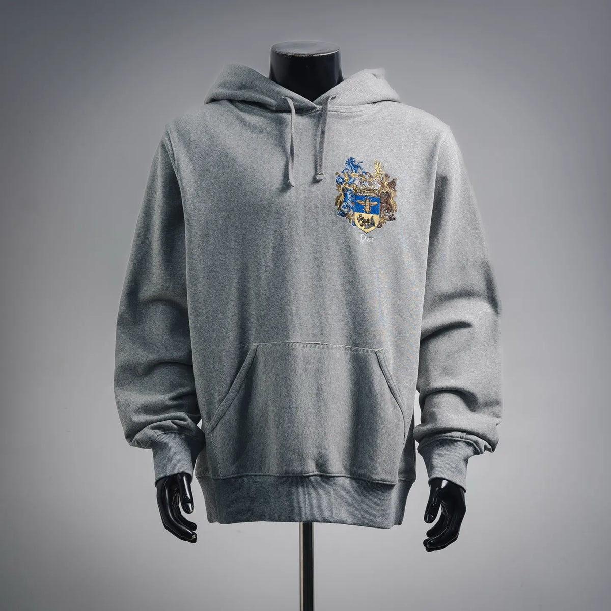 Gray pullover hoodie with hood, front kangaroo pocket, and embroidered crest logo