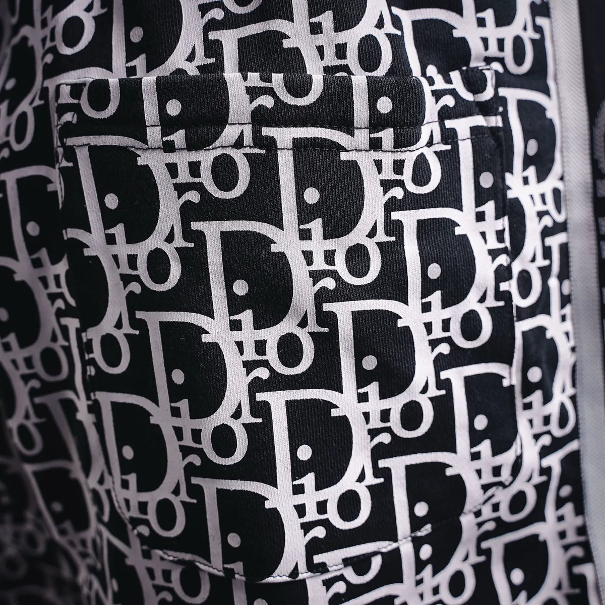Close-up of black-and-white Dior logo pattern on shorts fabric