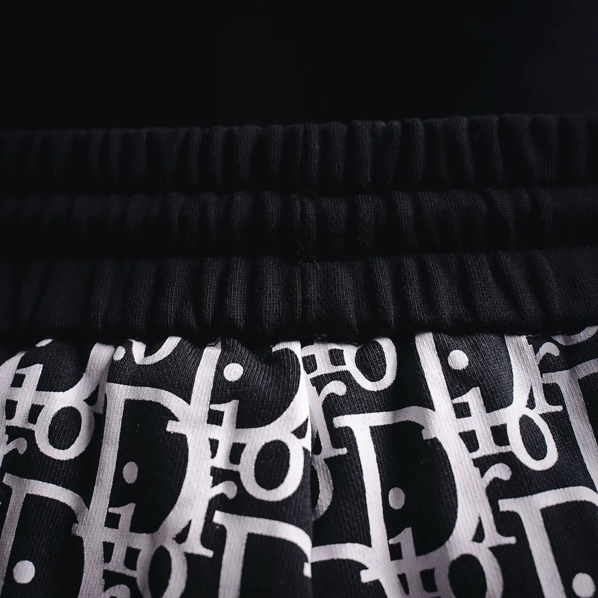 Elastic waistband and logo pattern hem detail on black-and-white Dior shorts