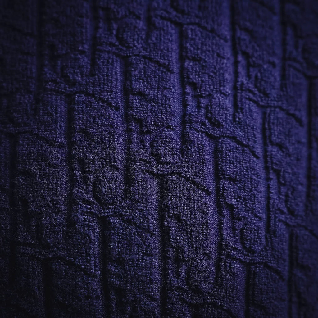Dark blue textured knit fabric close-up with raised pattern