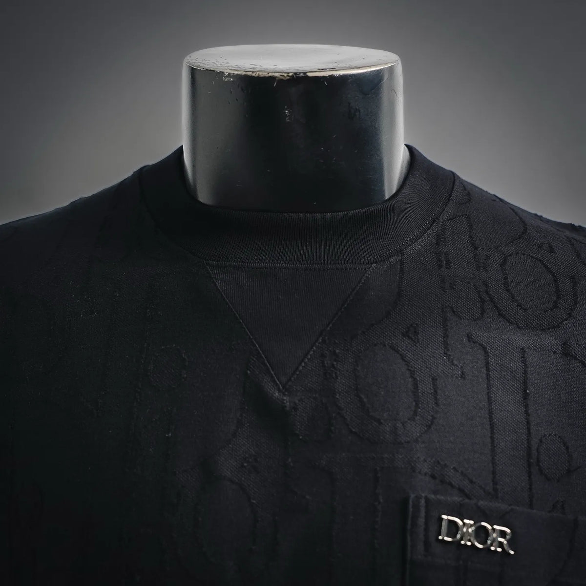 Black crewneck T-shirt close-up with textured Dior pattern and neckline seam