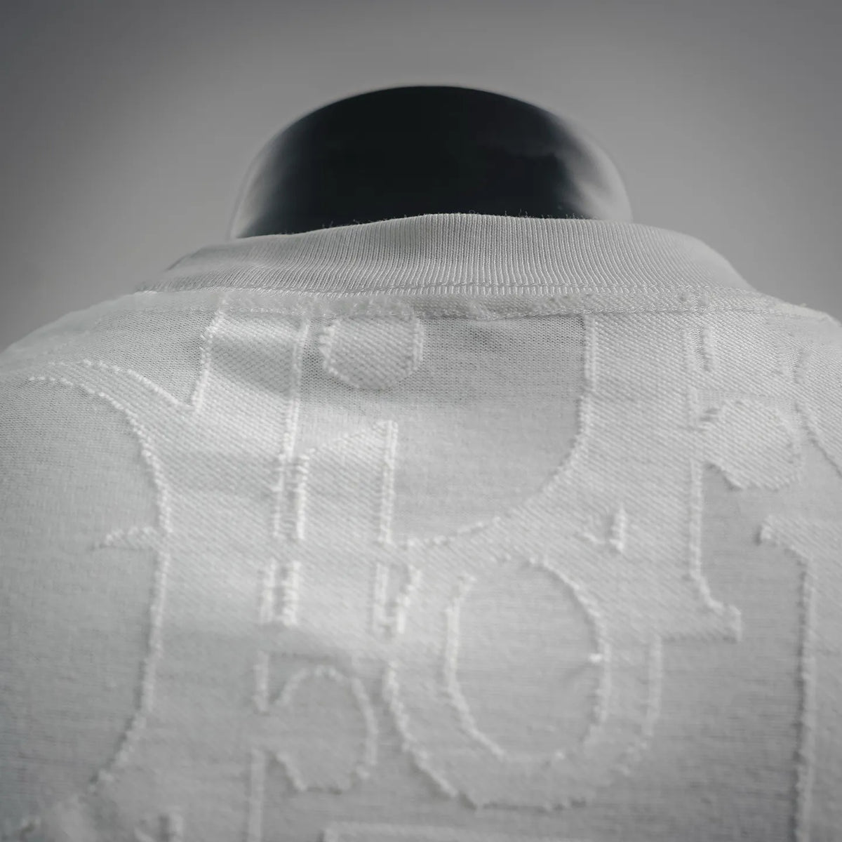 White Dior crewneck T-shirt close-up of embossed logo pattern on upper back