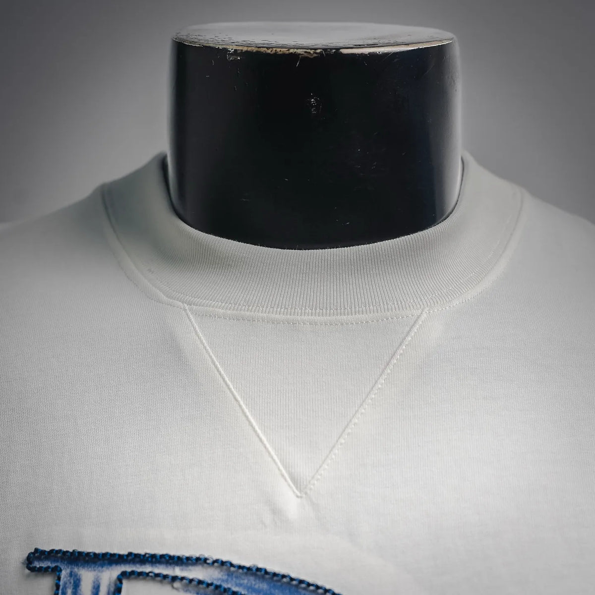 White T-shirt neckline with reinforced stitching and blue design edge.