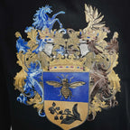 Black T-shirt featuring ornate blue, gold, and beige crest embroidery