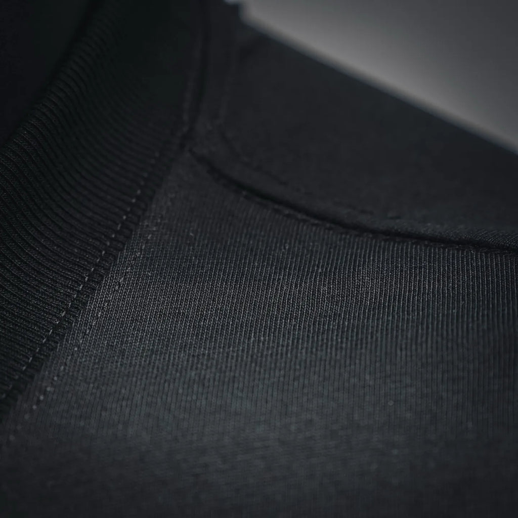 Black T-shirt fabric close-up showing seam stitching near the neckline