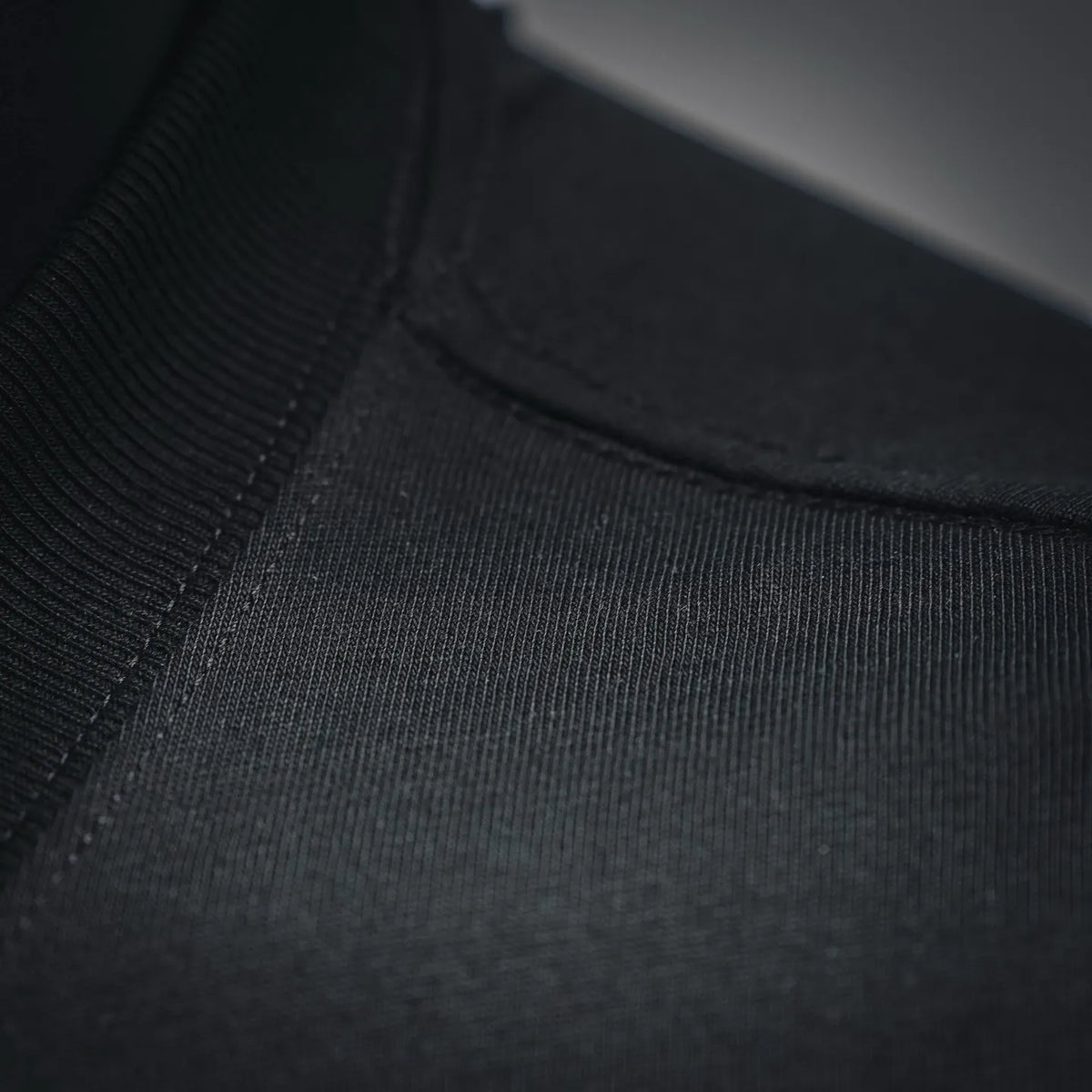 Black T-shirt fabric close-up showing seam stitching near the neckline