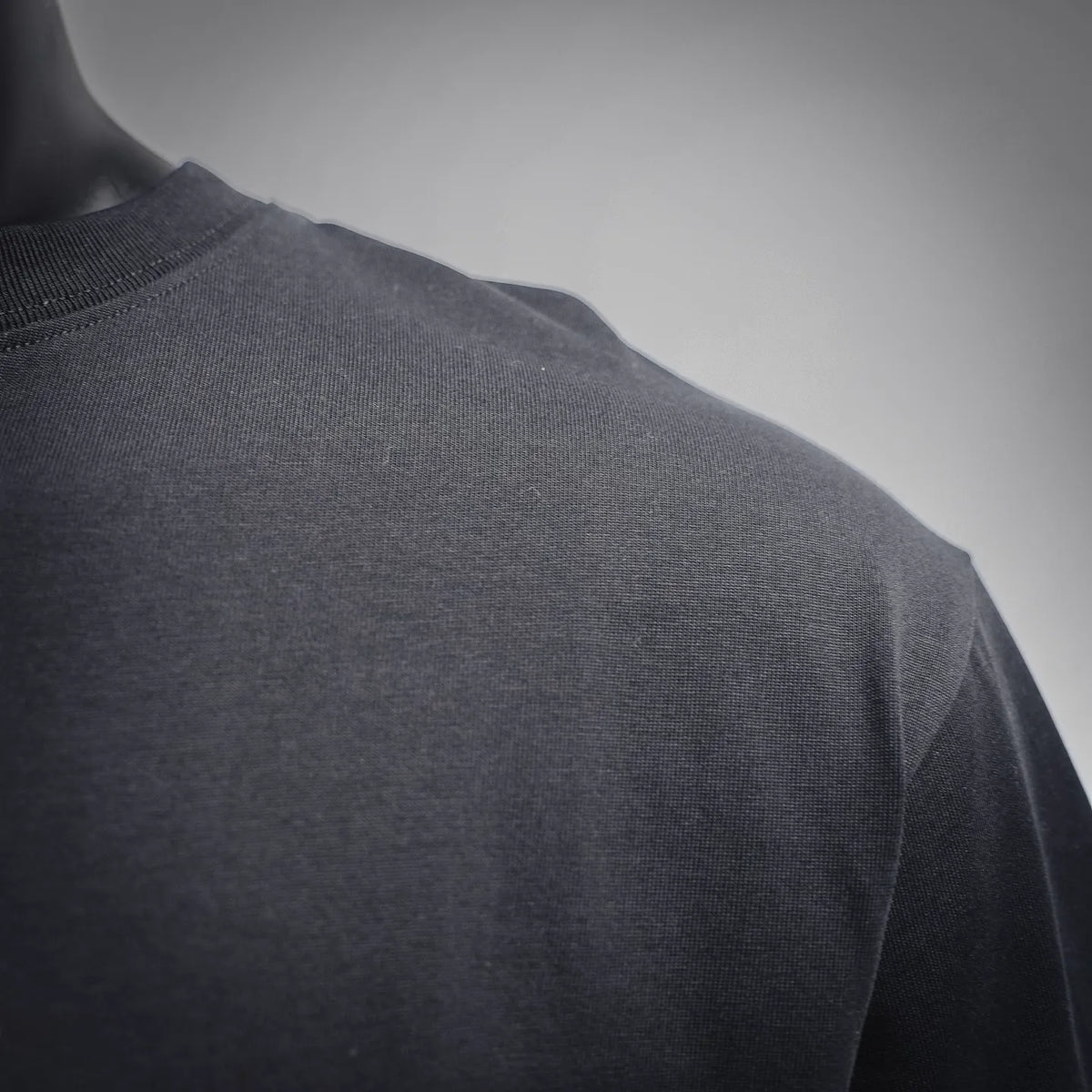 Men's T-shirt side close-up showing dark fabric drape and stitched panel