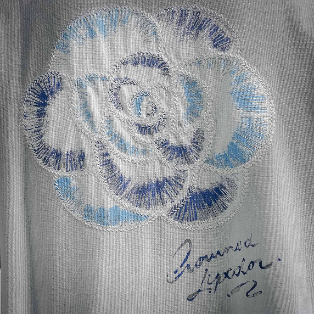 White Dior T-shirt close-up of blue stitched swirl emblem
