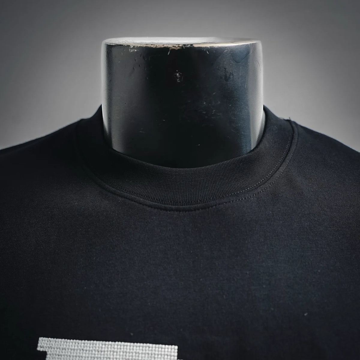 Dior black crew-neck T-shirt close-up, ribbed collar and subtle fabric texture