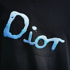 Dior short-sleeve T-shirt close-up, dark fabric, large blue “Dior” logo embroidery