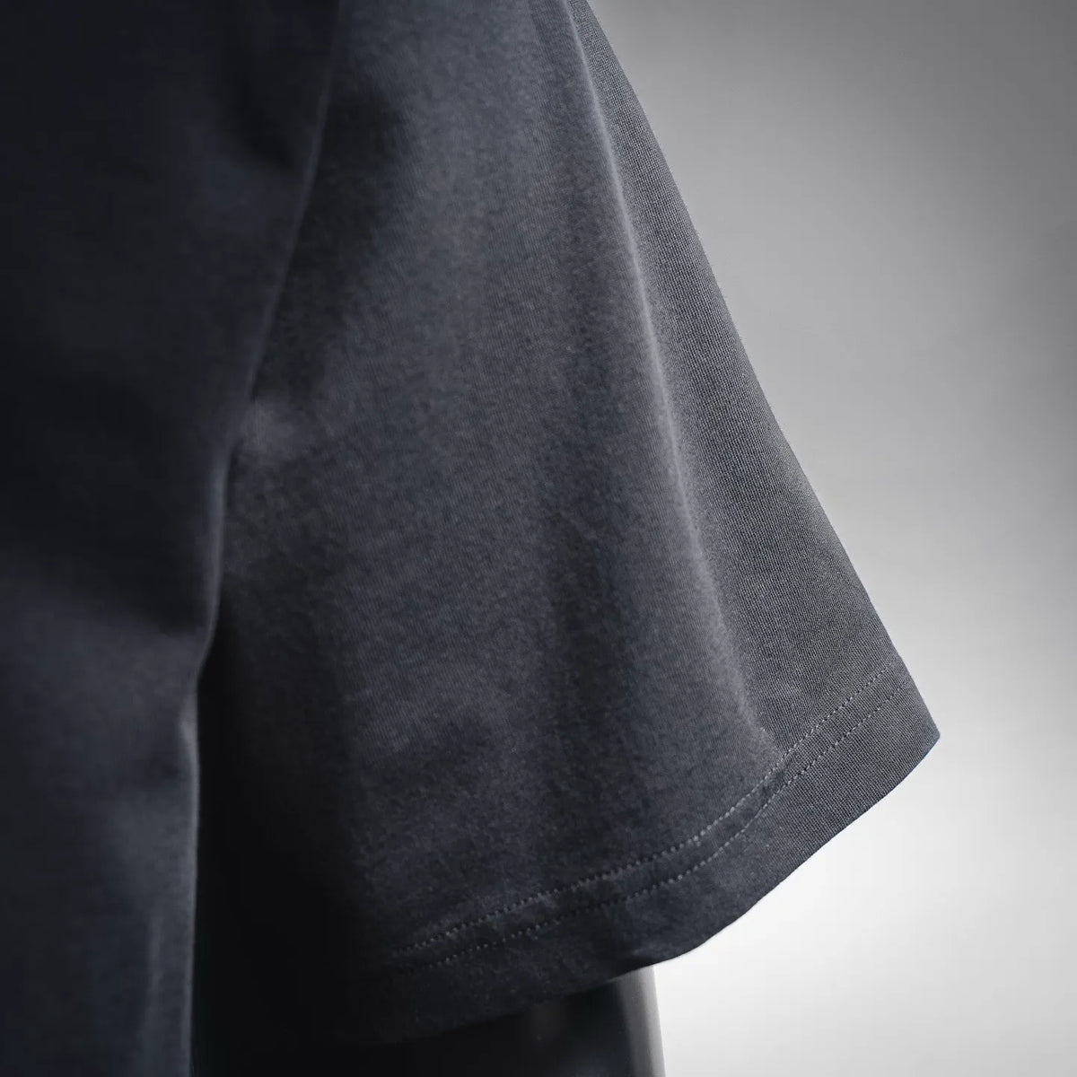 Dior short-sleeve T-shirt sleeve hem close-up, dark fabric and edge stitching