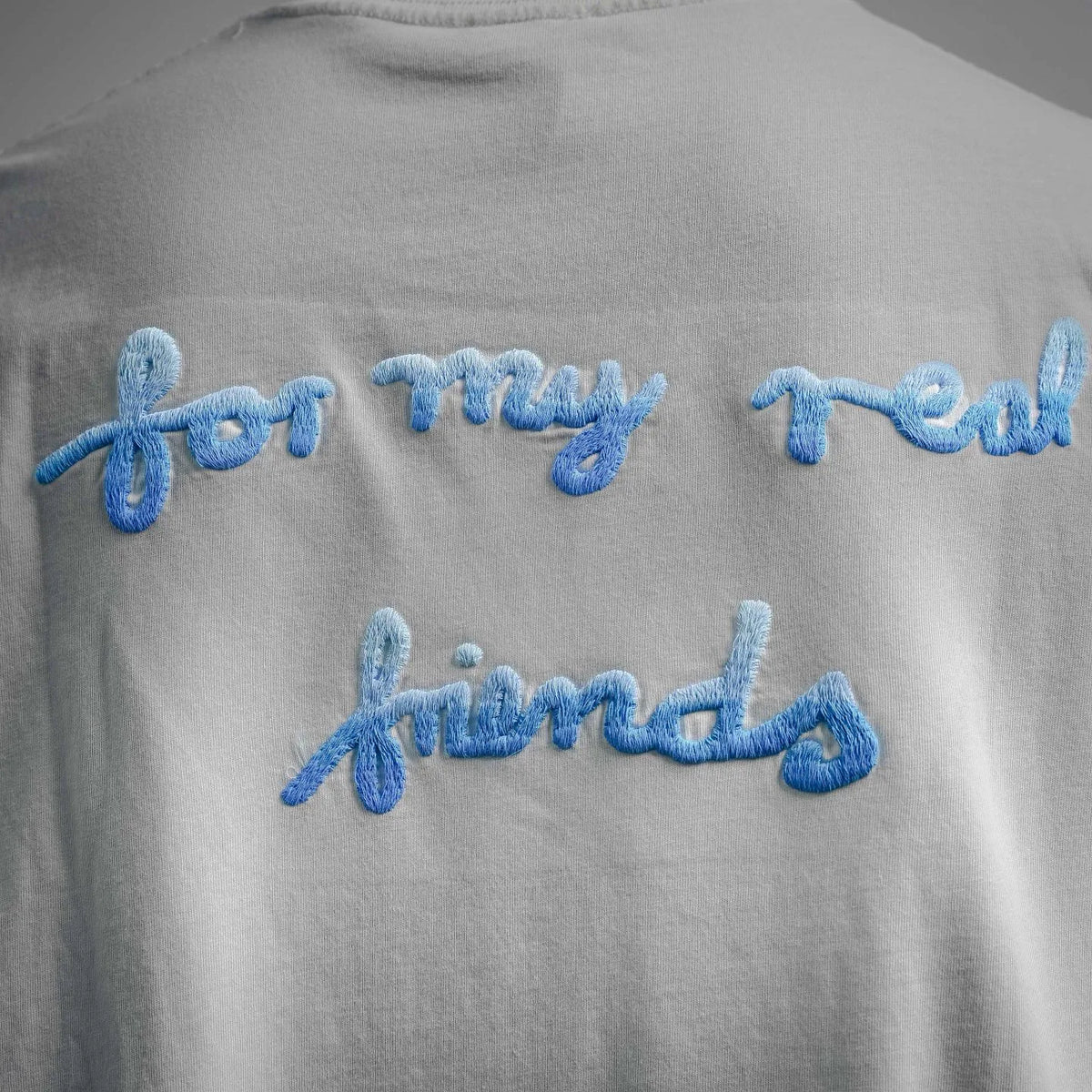 White T-shirt back close-up with blue embroidered lettering