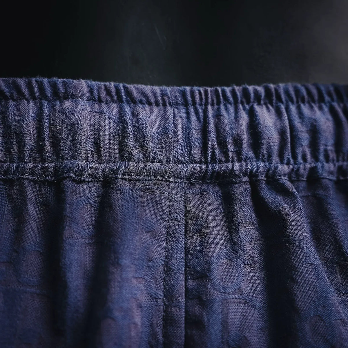 Navy shorts waistband close-up with elastic trim and center seam