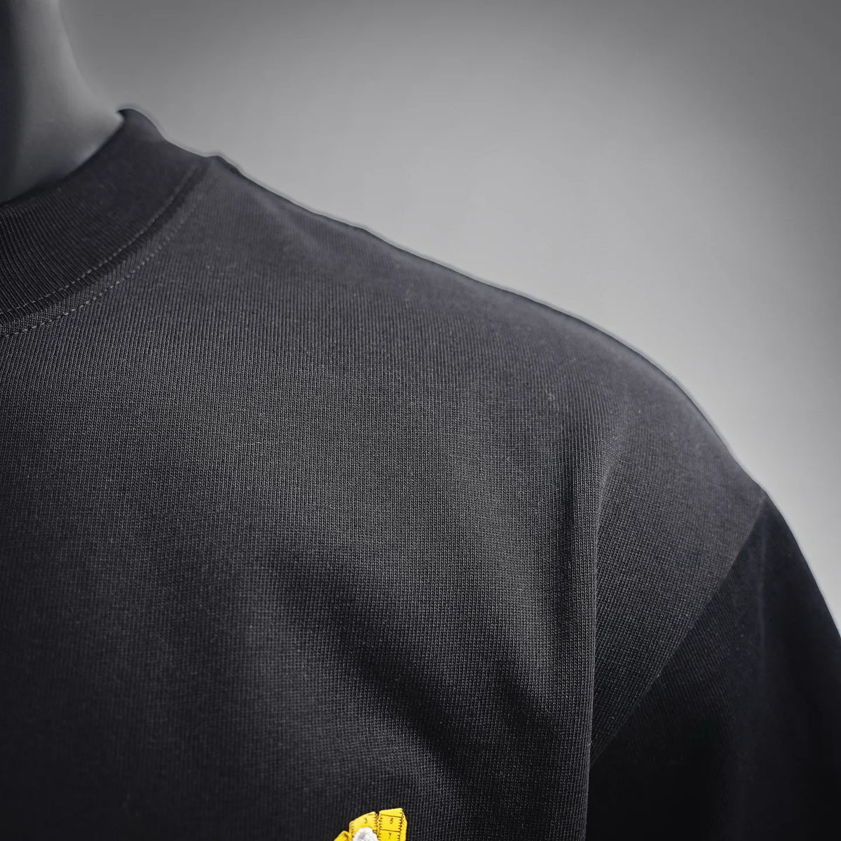 Black T-shirt fabric close-up at shoulder seam and sleeve edge