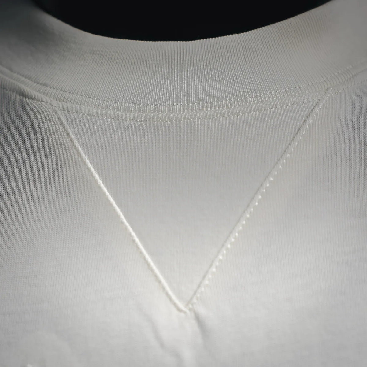 White T-shirt neckline with V-shaped seam and visible stitching close-up