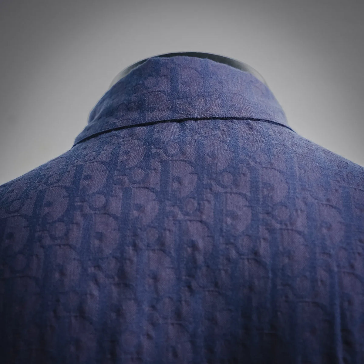 Navy shirt back yoke close-up with subtle Dior monogram texture and seam line.