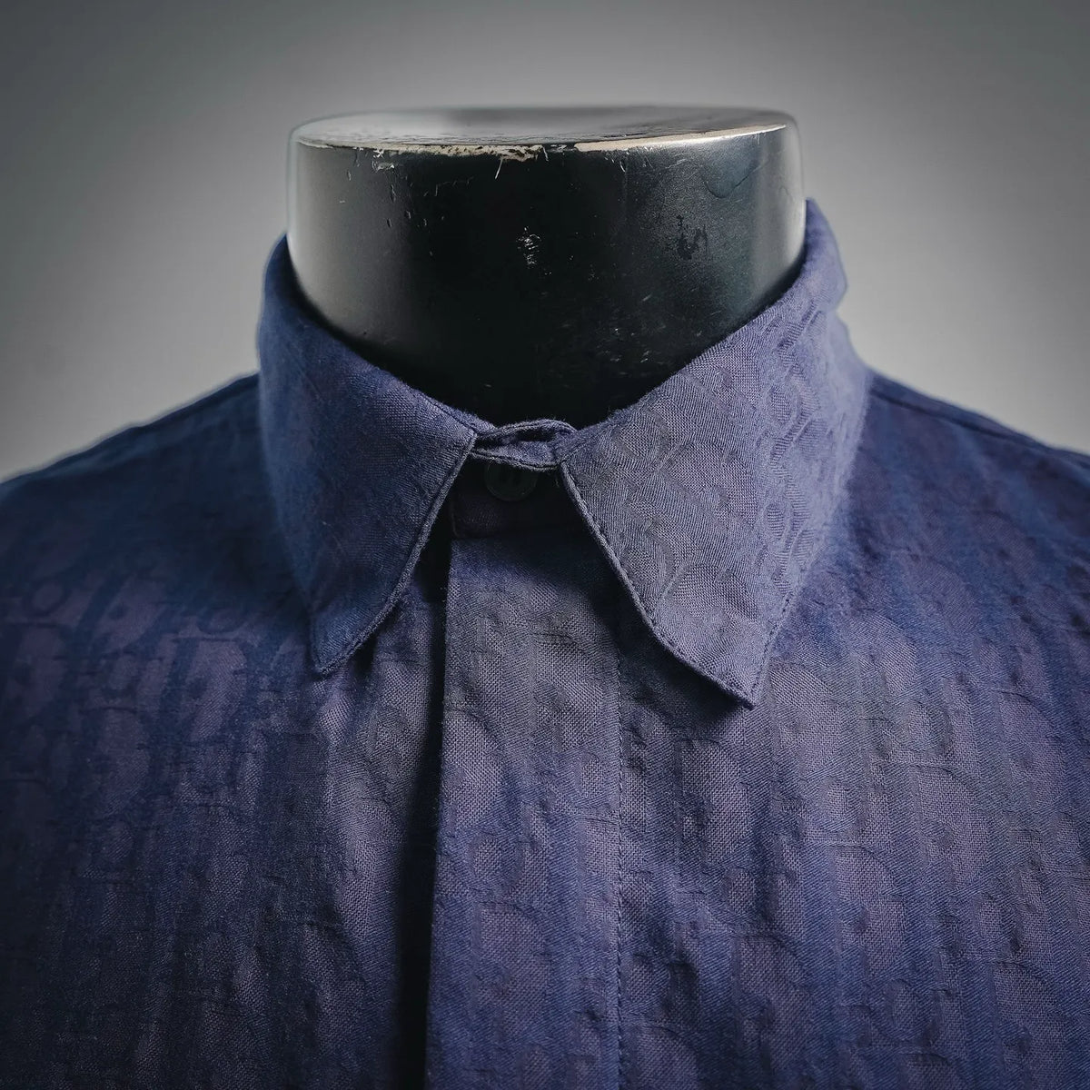 Navy short-sleeve shirt with pointed spread collar and top button closed.