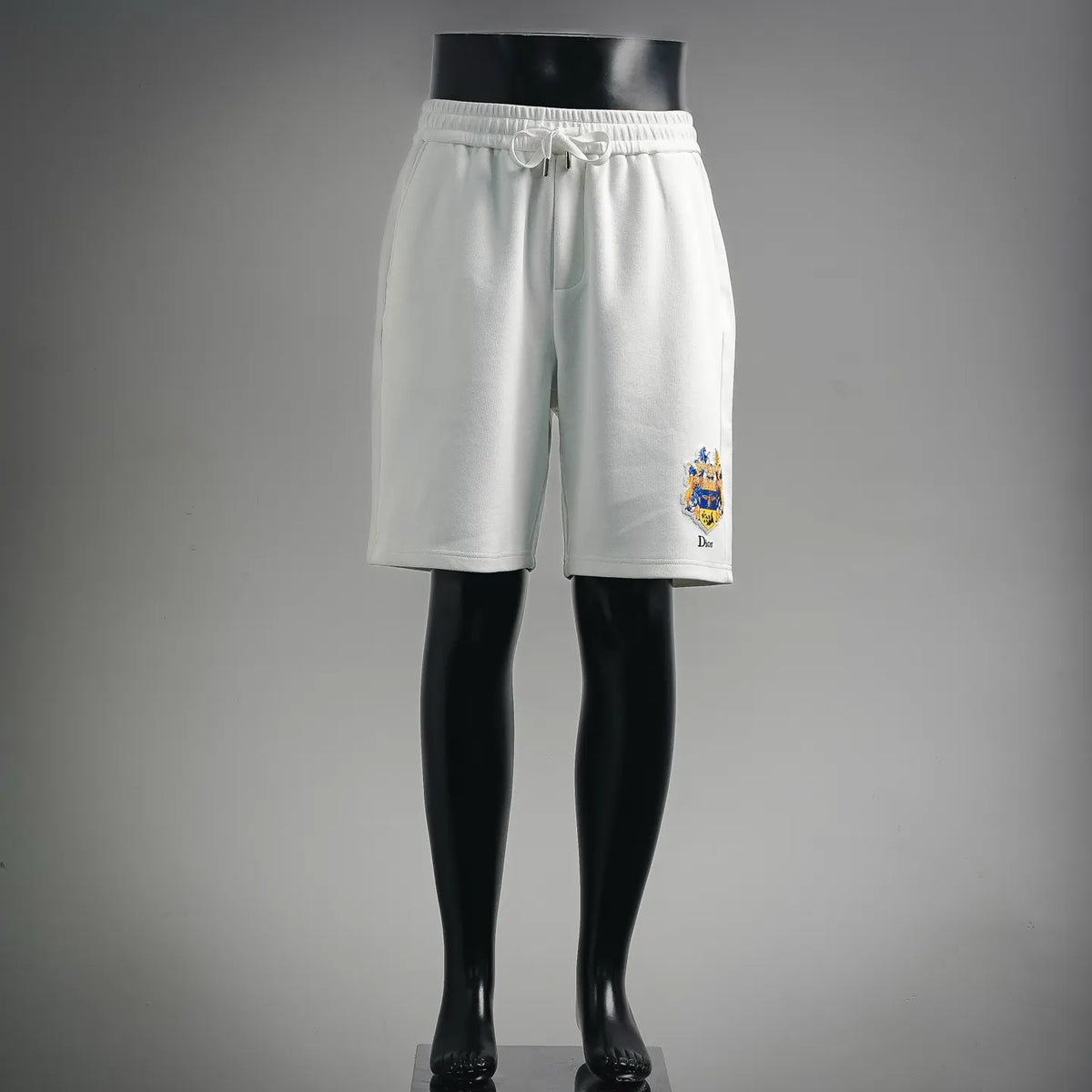 White shorts with elastic waistband and small crest logo on the leg