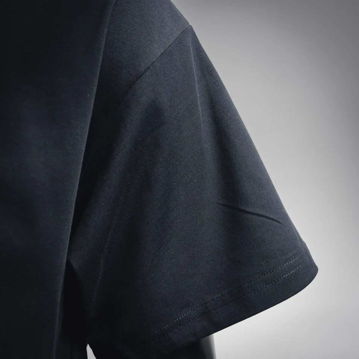 Dior T-shirt sleeve close-up with visible stitching seam on dark fabric