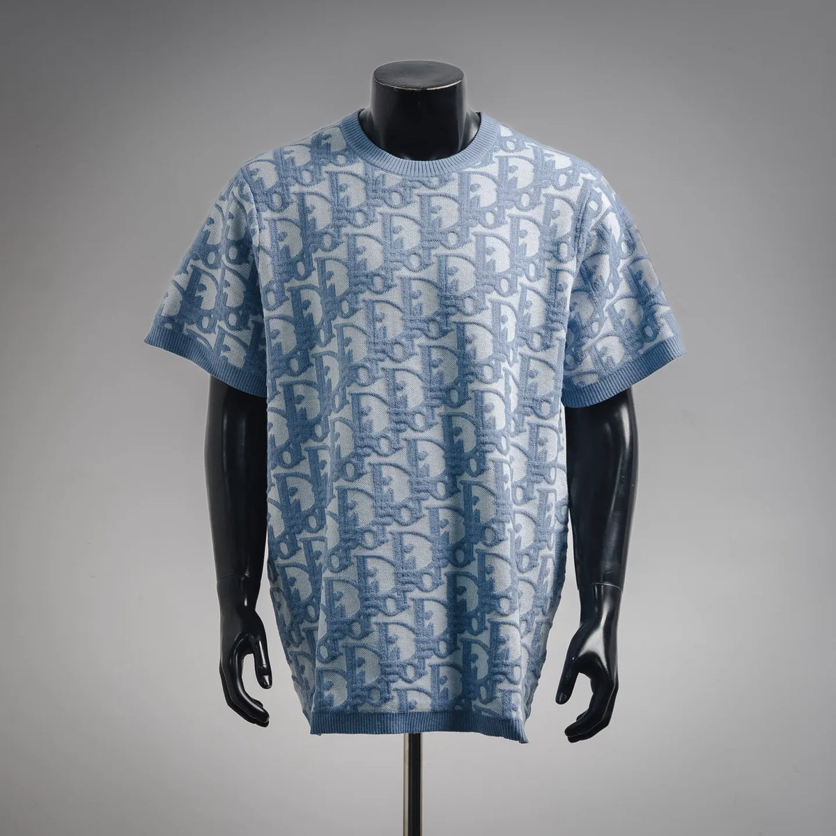 Light blue knit short-sleeve crewneck sweater with repeating Dior pattern on front.