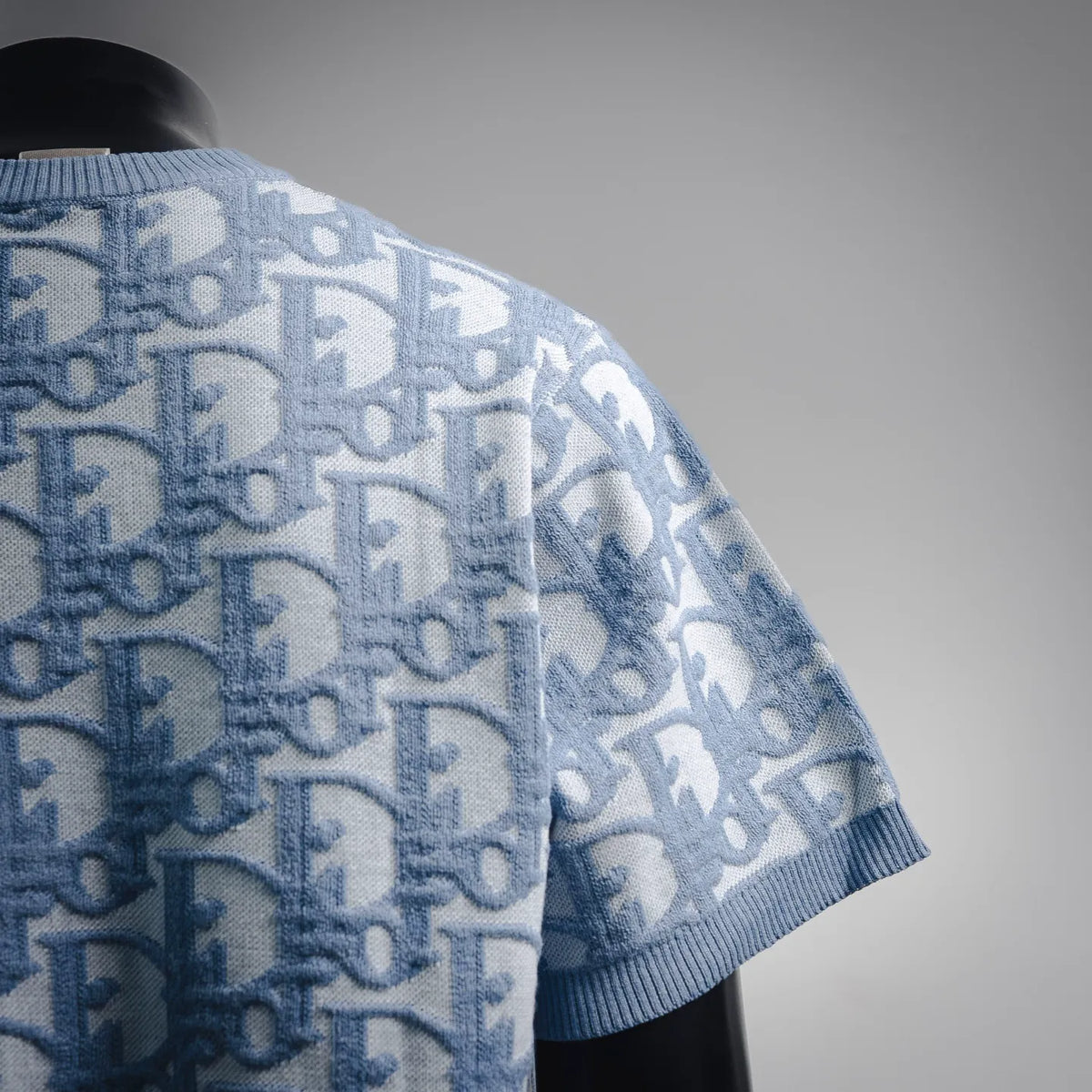 Light blue ribbed collar knit with repeating Dior monogram pattern, short-sleeve.