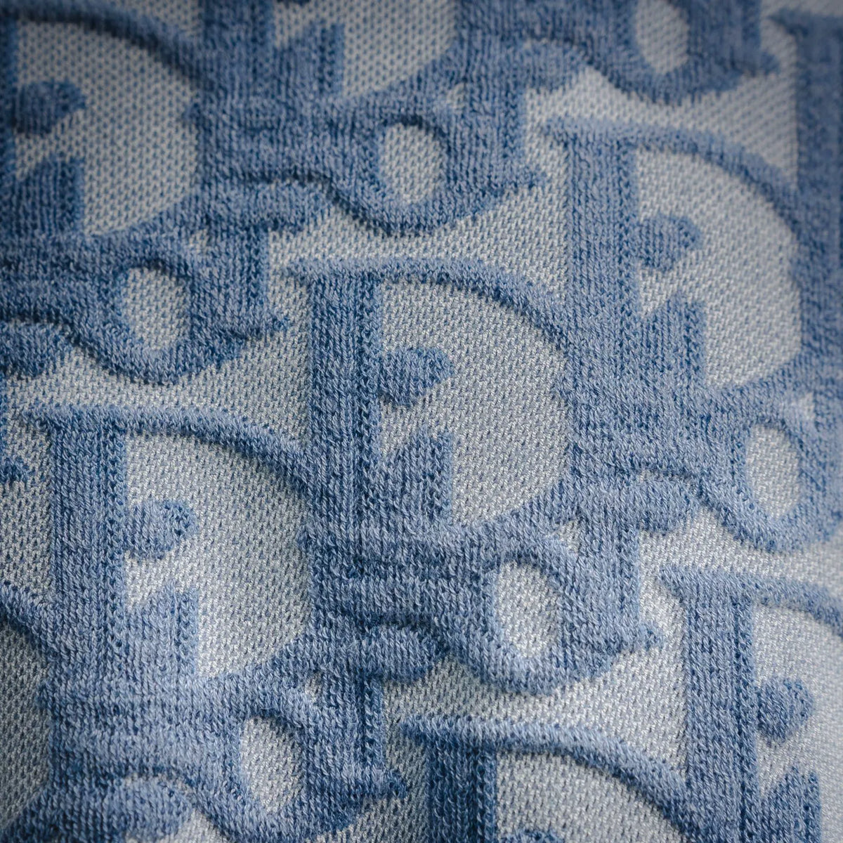 Light blue woven-knit fabric with repeating Dior monogram pattern detail.