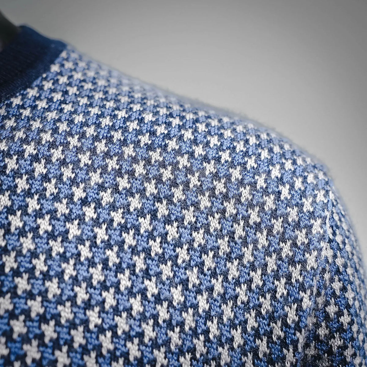 Blue and white houndstooth knit sweater fabric close-up with fine texture