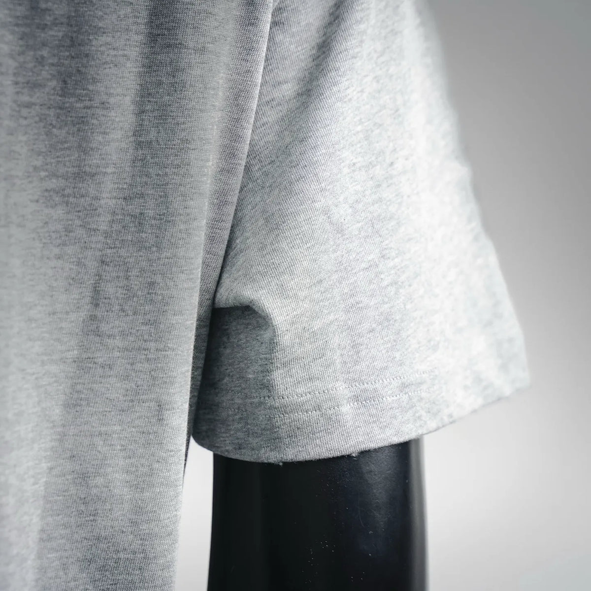Light gray T-shirt sleeve hem with slight drape over mannequin arm
