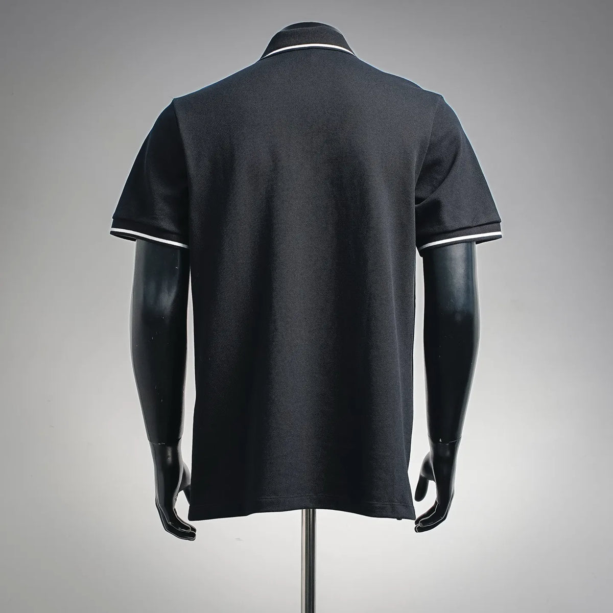Dior dark polo shirt on mannequin, back view, short sleeves, ribbed collar with white trim