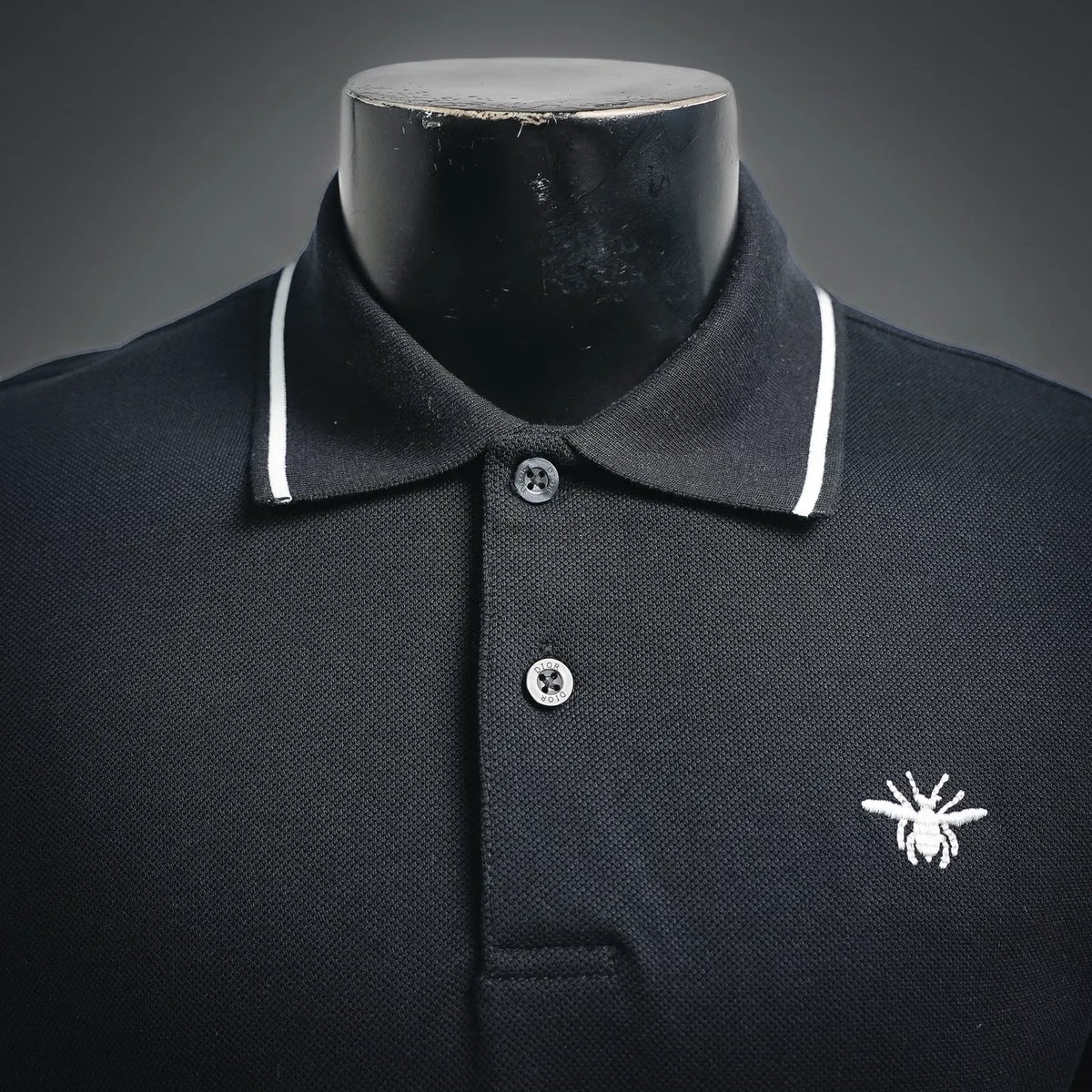 Dior dark polo shirt neckline with button placket and white-trim collar, logo at chest