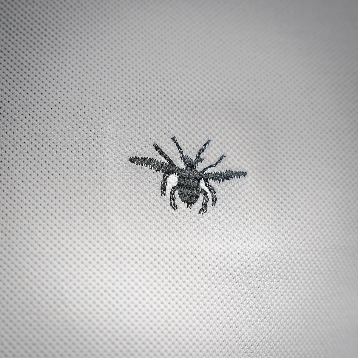 Bee logo embroidery on white polo fabric