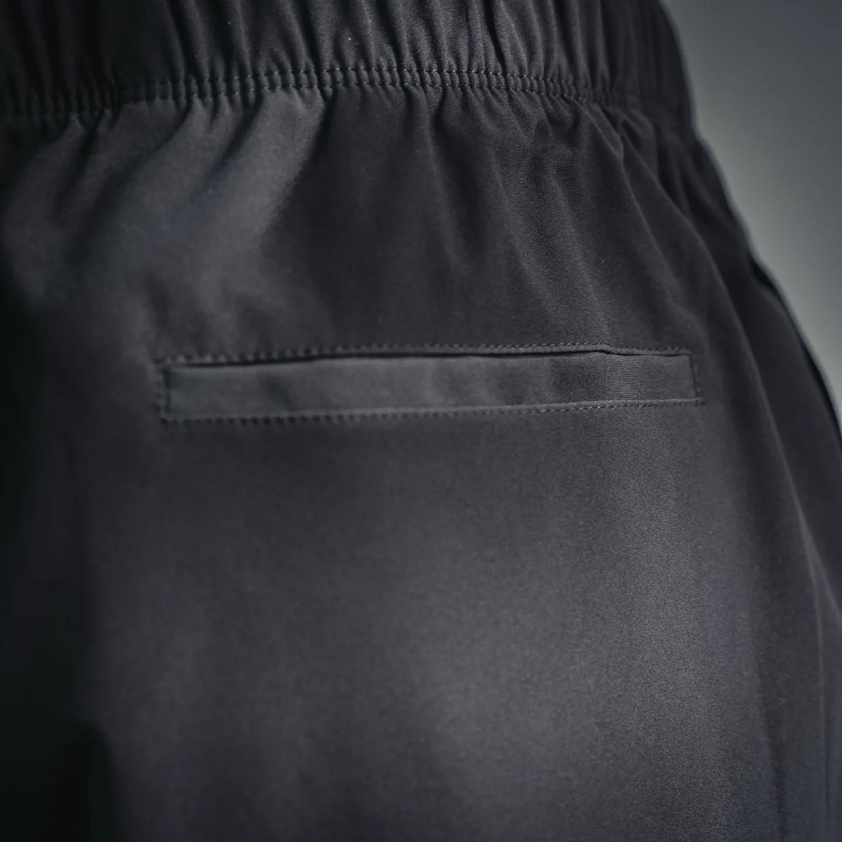 Front pocket flap and stitched seams on black shorts