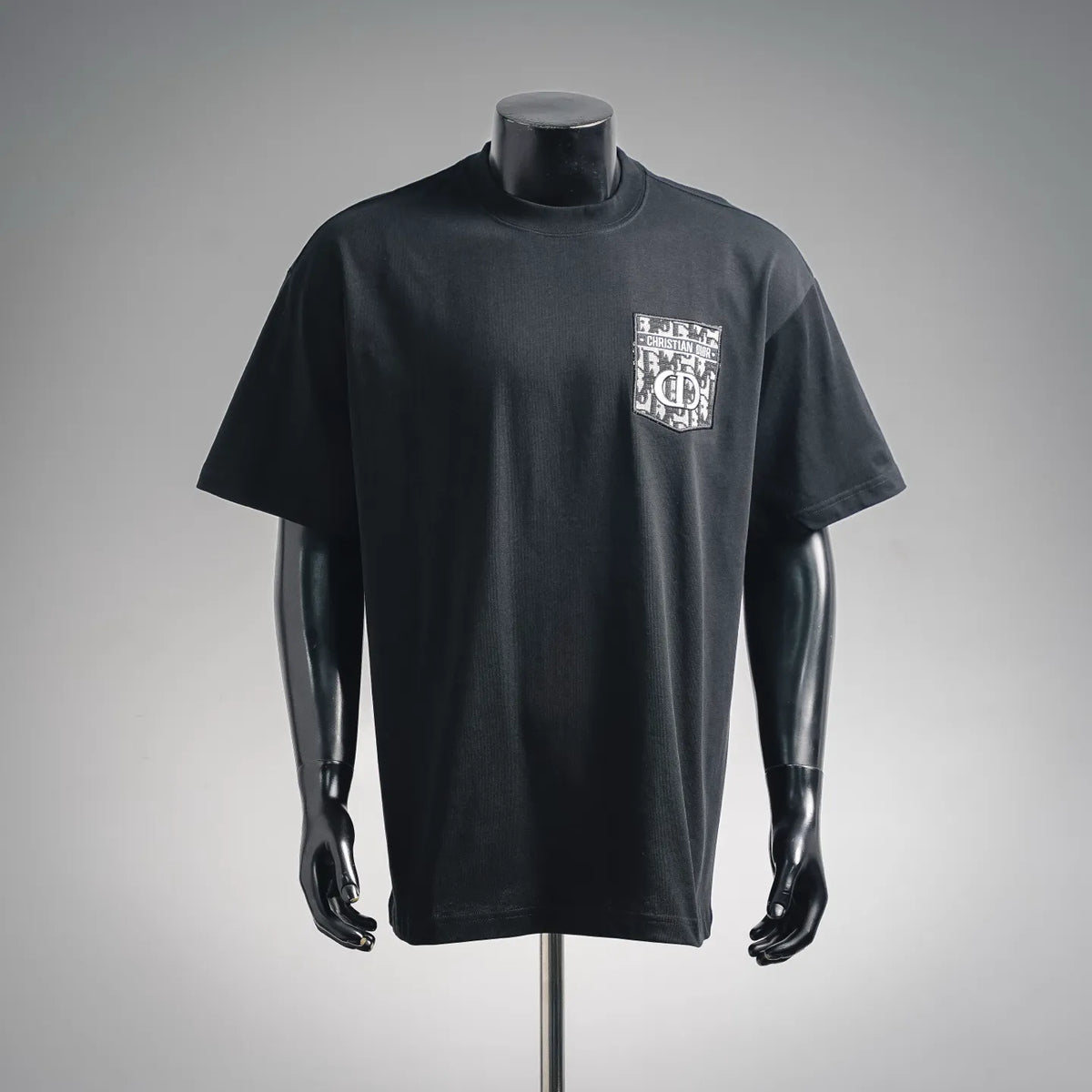 Black crewneck T-shirt with short sleeves and Dior logo patch on chest.
