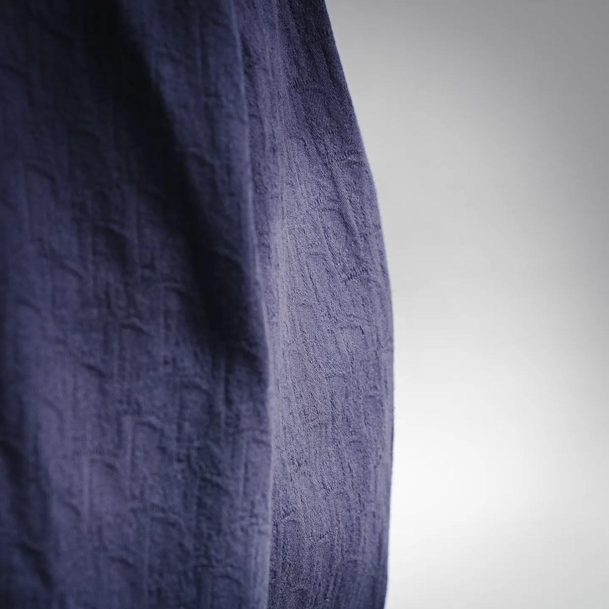 Dark navy textured shirt side panel with visible seam and fabric weave
