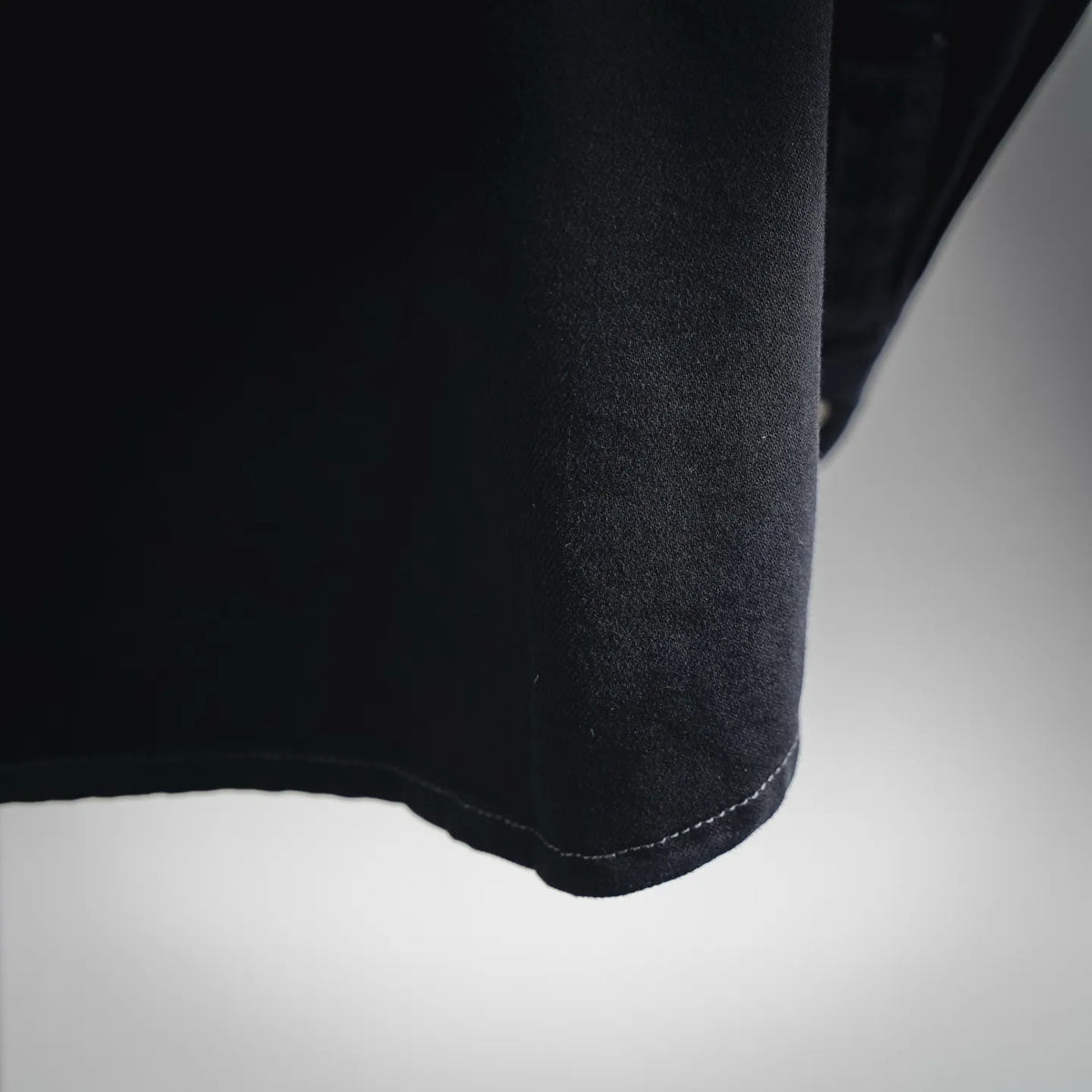 Black shirt hem detail with curved stitched edge