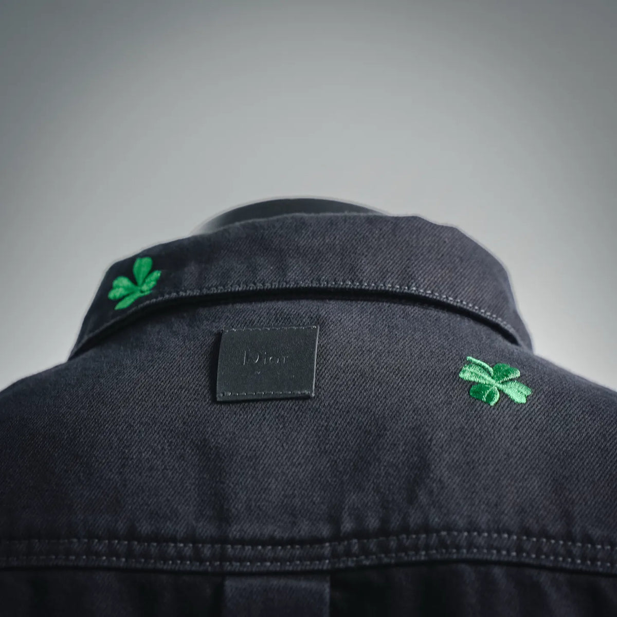 Black shirt neckline with internal label and green clover patches on shoulders